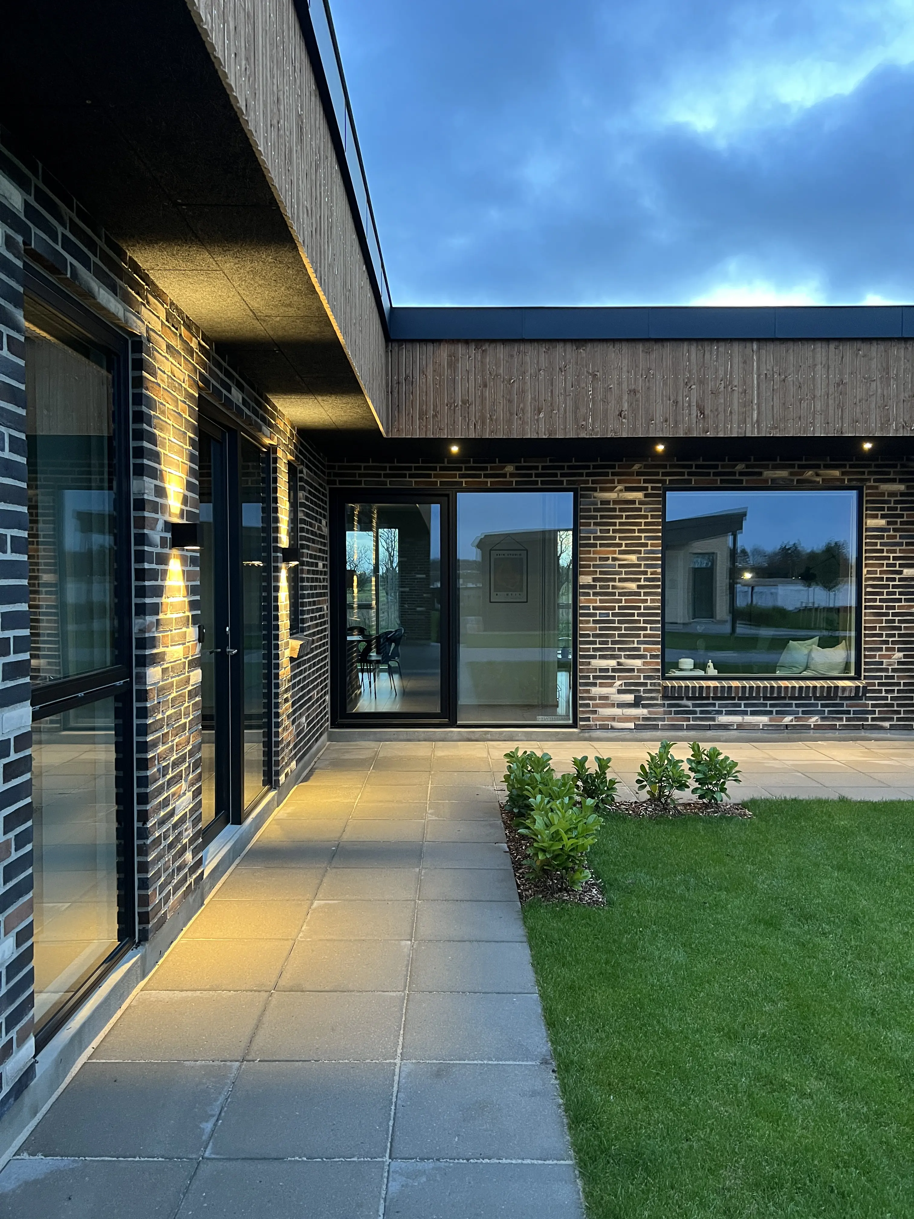 Vinkelhus set om aftenen med lys i murværket